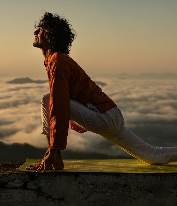 Silhouette of a person in a yoga pose against a sunrise.