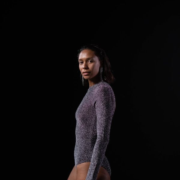 Woman in a calm yoga pose in a dark room with soft light.